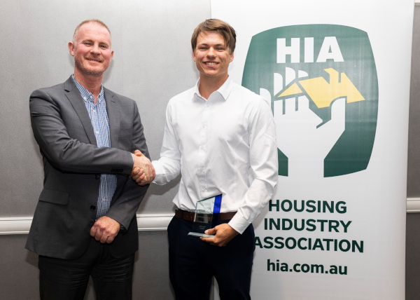 Housing Industry Association Ltd. HIA two men shaking hands with an HIA sign to the side.