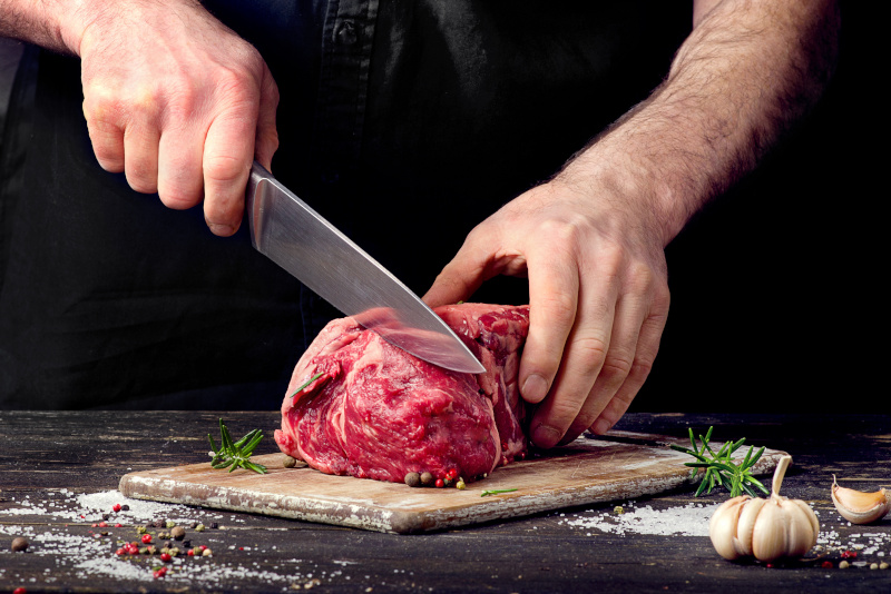 Man cutting raw beef meat. Australian Meat Industry Council (AMIC) - Sydney, New South Wales
